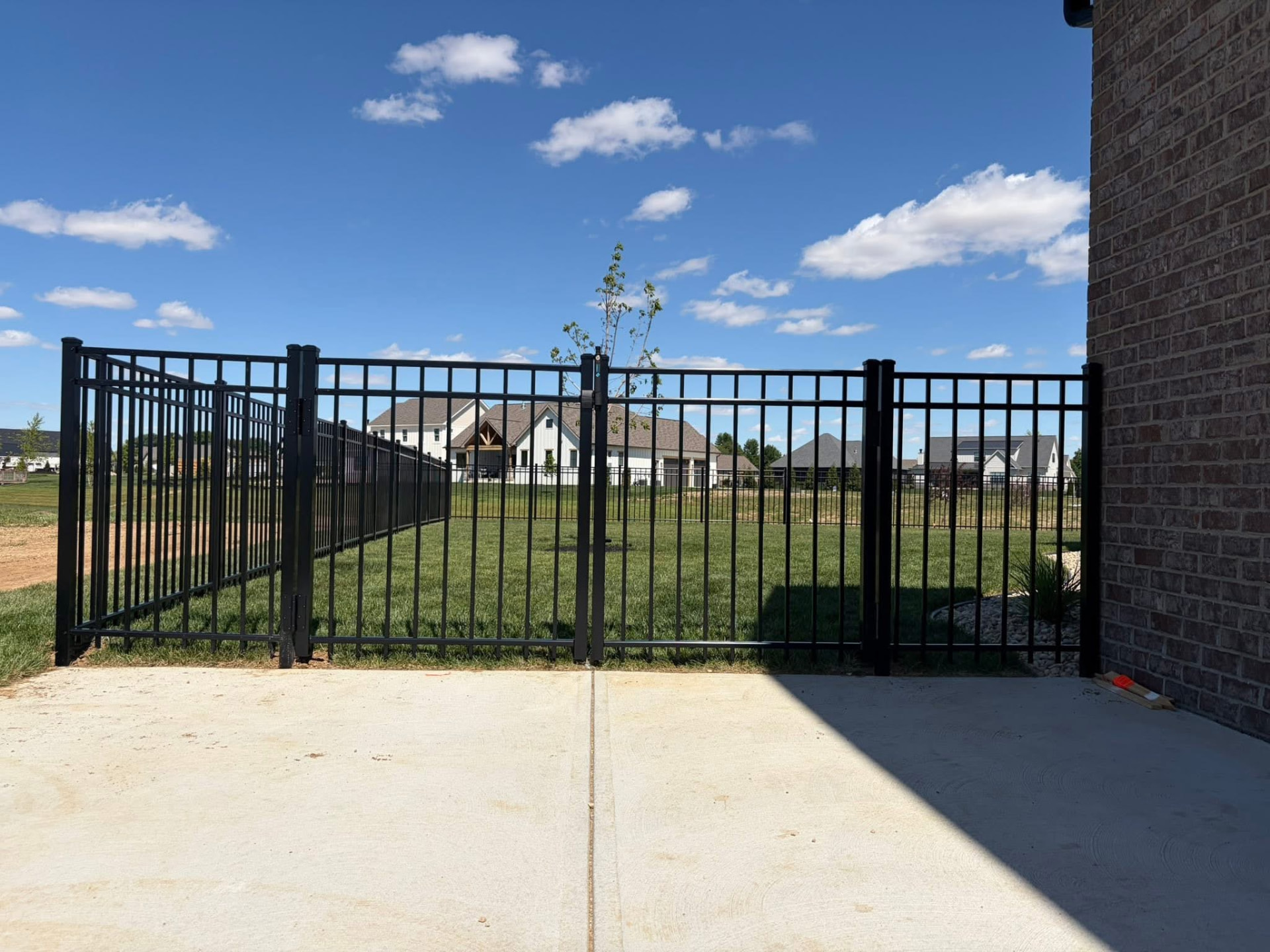 Black aluminum fence and double gate behind a brick home